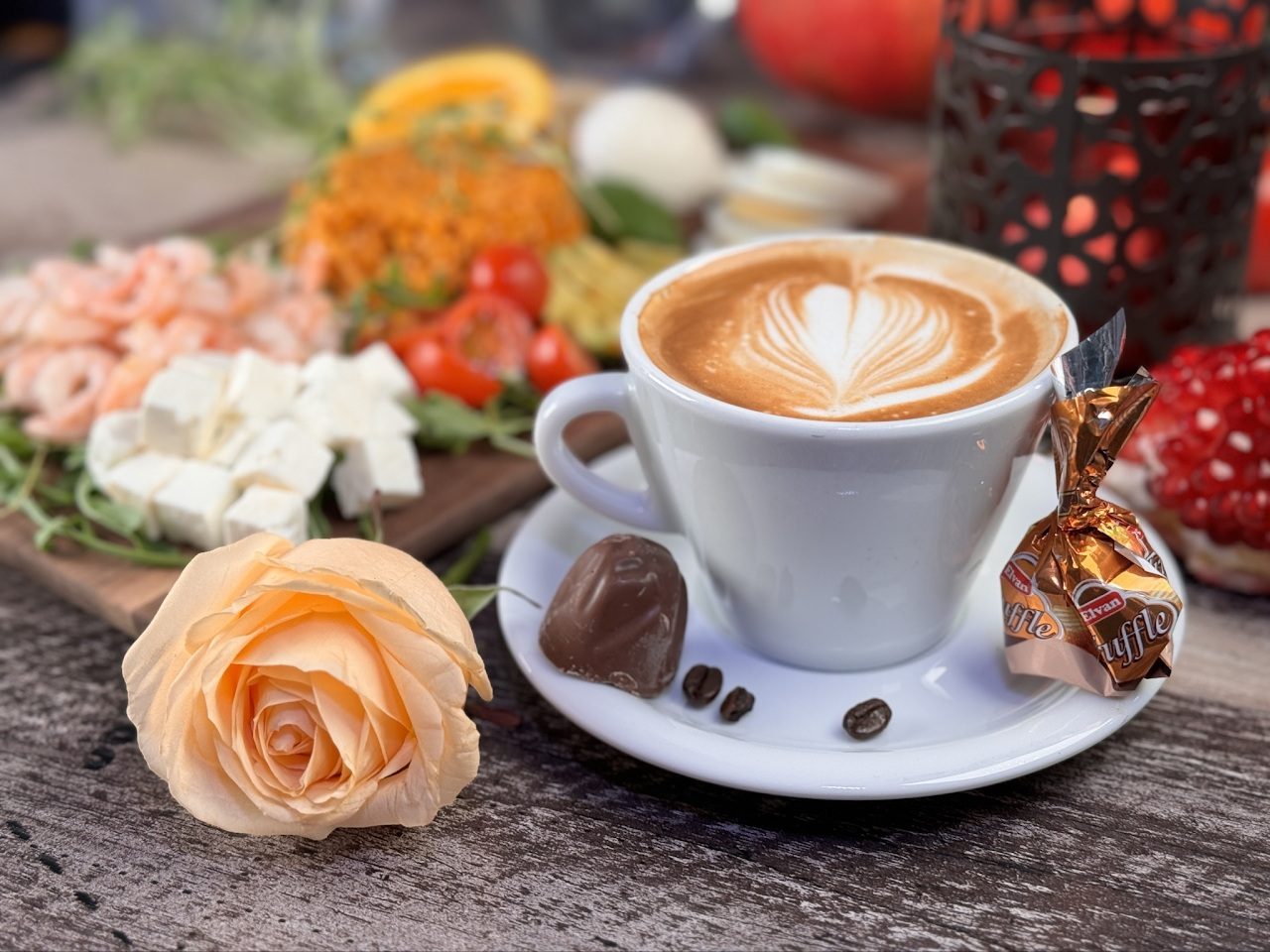 Cappuccino med latte art bredvid en ros
