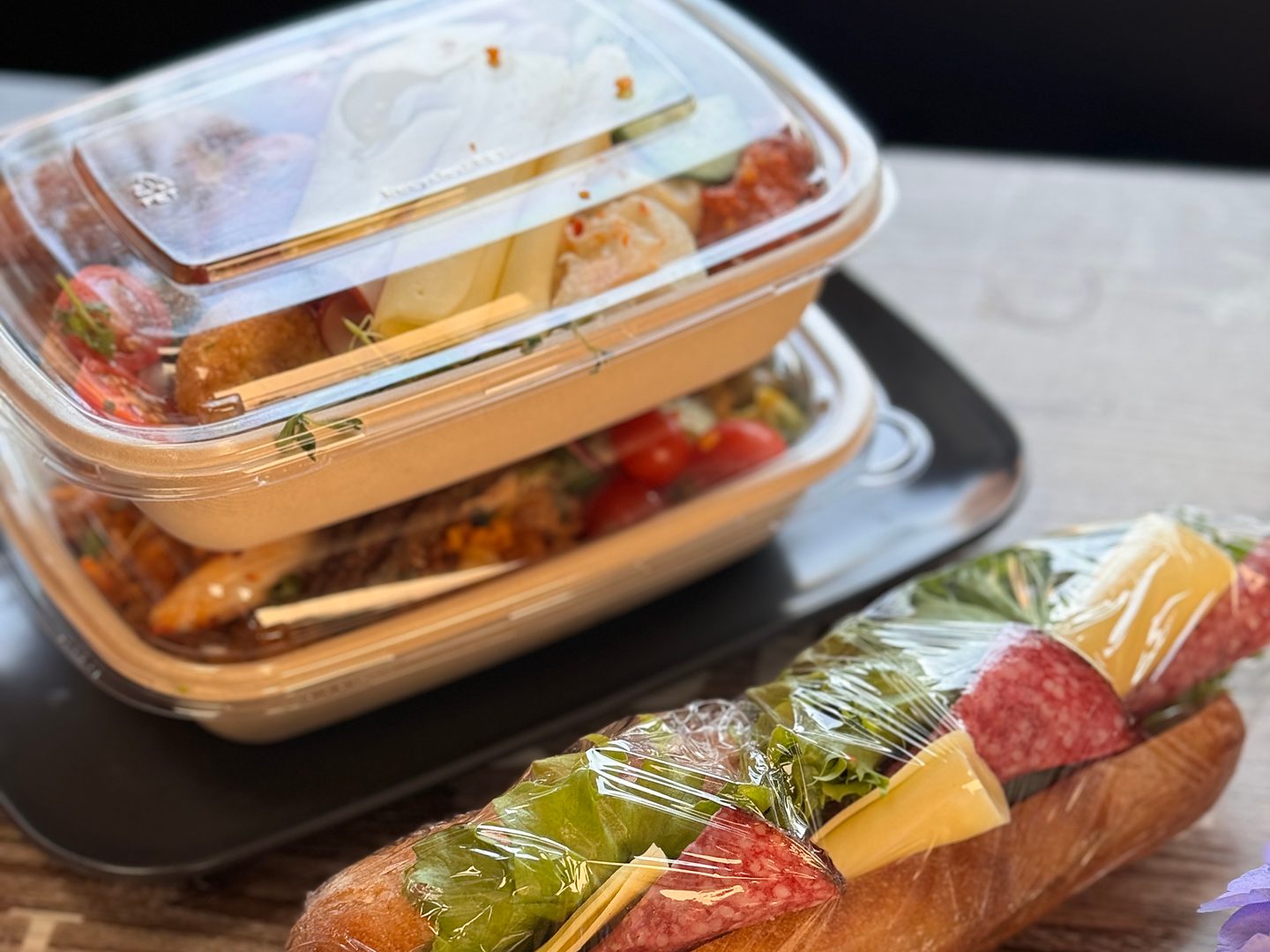 Cateringmat packad i lådor med lock och en inplastad baguette, redo för leverans