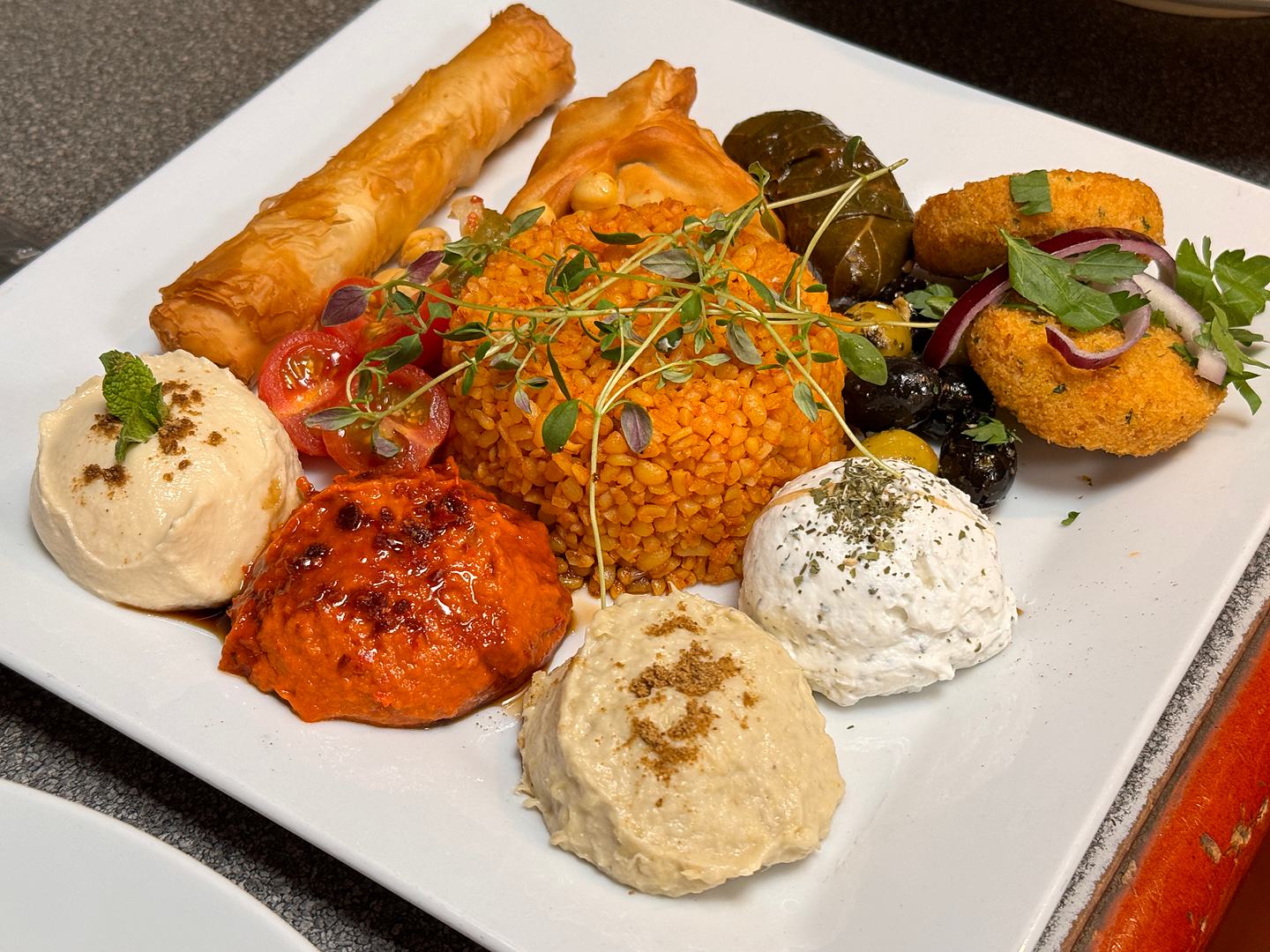 Närbild på mezetallrik med hummus, auberginröra, bulgur och falafel